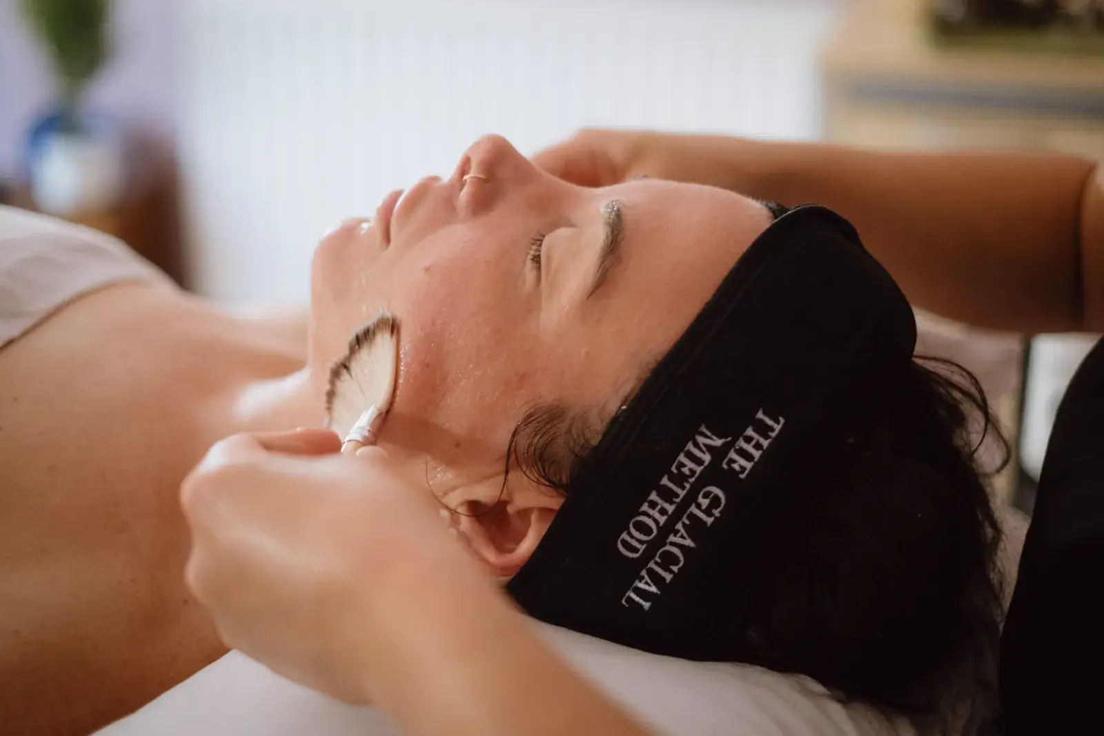 A fan brush applying product during a facial